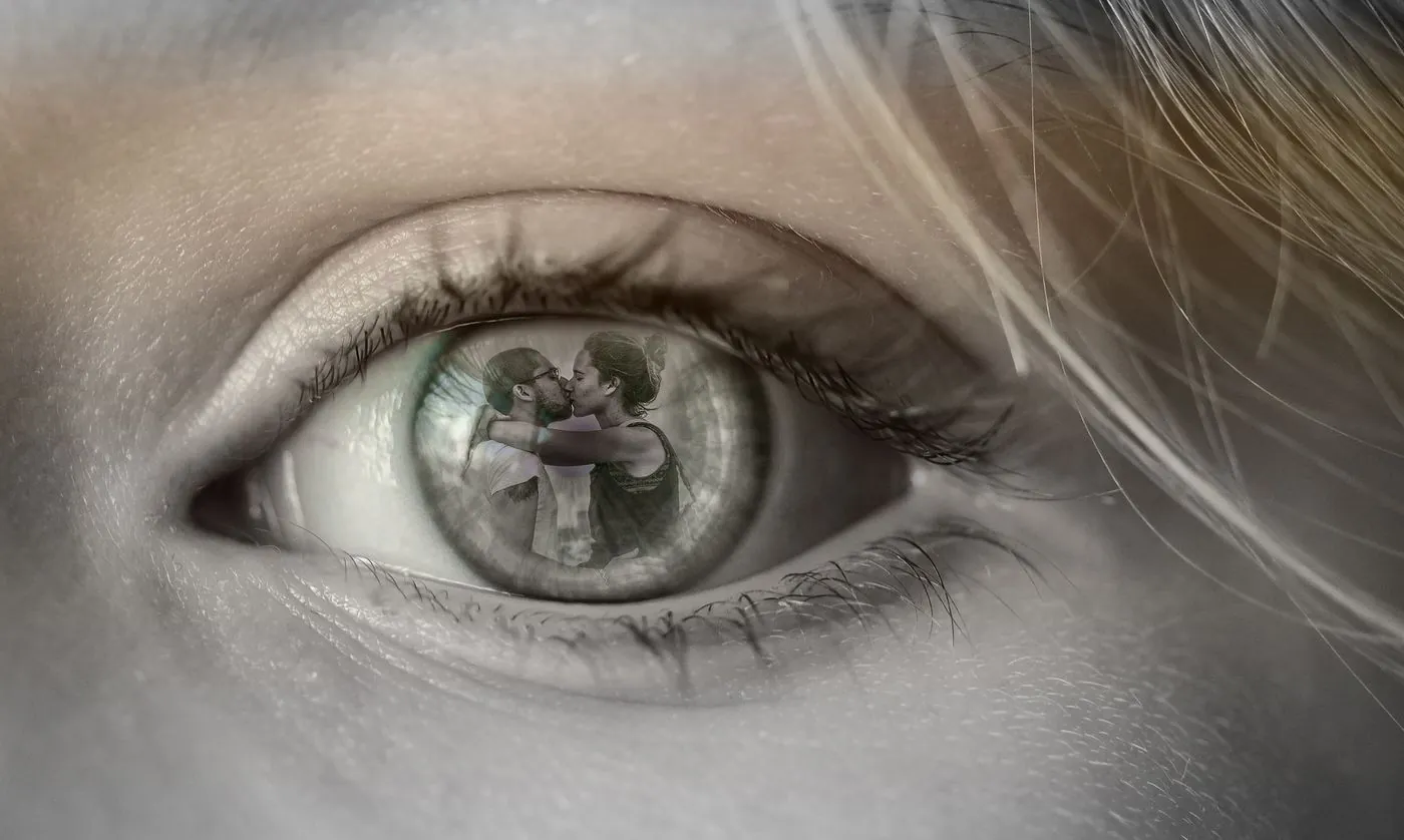 La anatomía del arrepentimiento: por qué el perdón no basta para sanar una infidelidad. 3 Primer plano de un ojo en el que se refleja una pareja besándose, imagen sobre los límites de la fidelidad