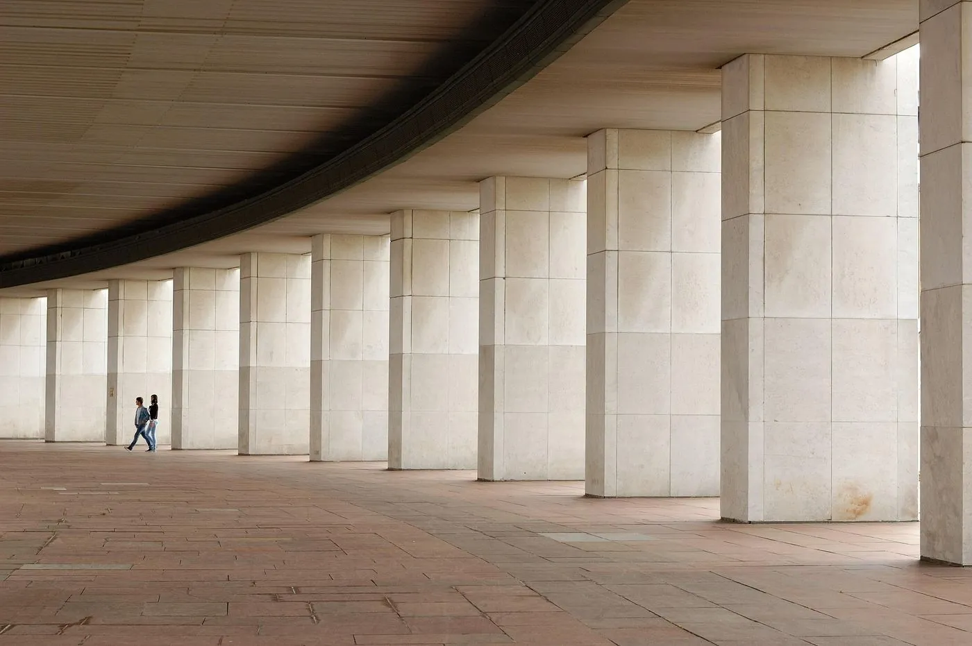 La anatomía del arrepentimiento: por qué el perdón no basta para sanar una infidelidad. 5 Hilera de columnas de piedra con dos personas caminando al fondo, imagen sobre los pilares de una relación de pareja